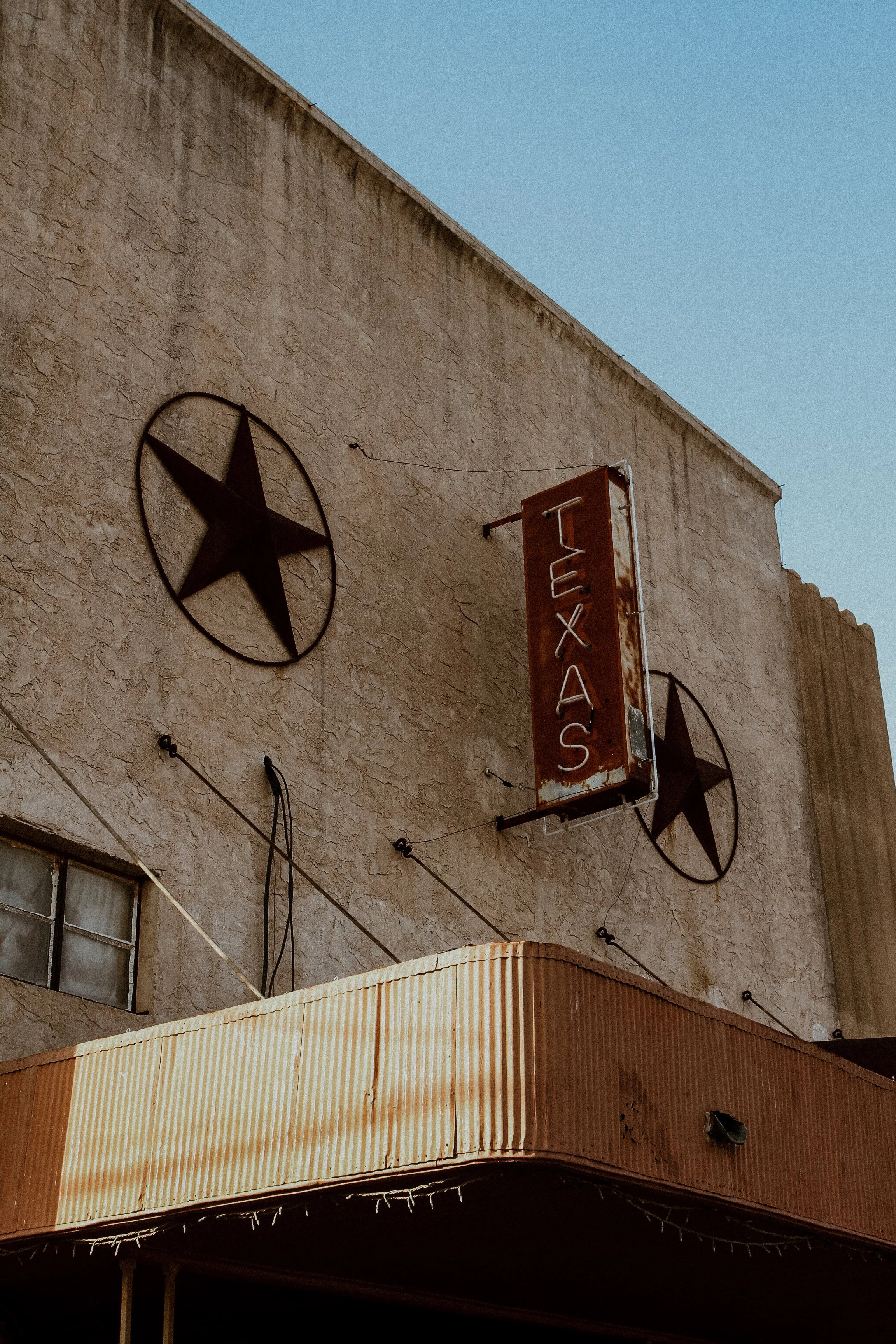 Exterior of a building with two large black star decorations on the wall and a red sign that says "TEXAS".