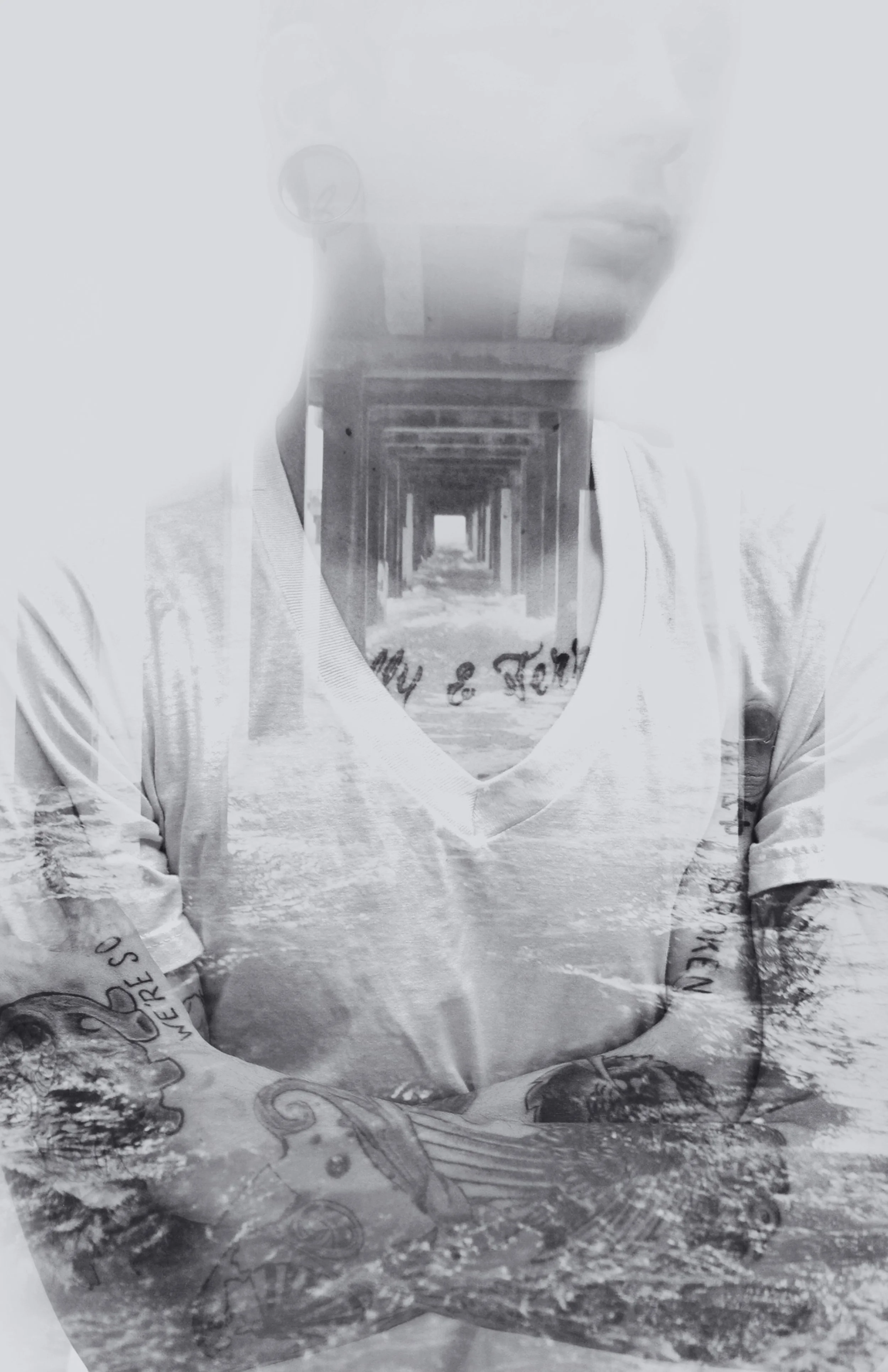A double exposure black and white photo combining a person wearing glasses and a t-shirt with a nature scene of trees and water.