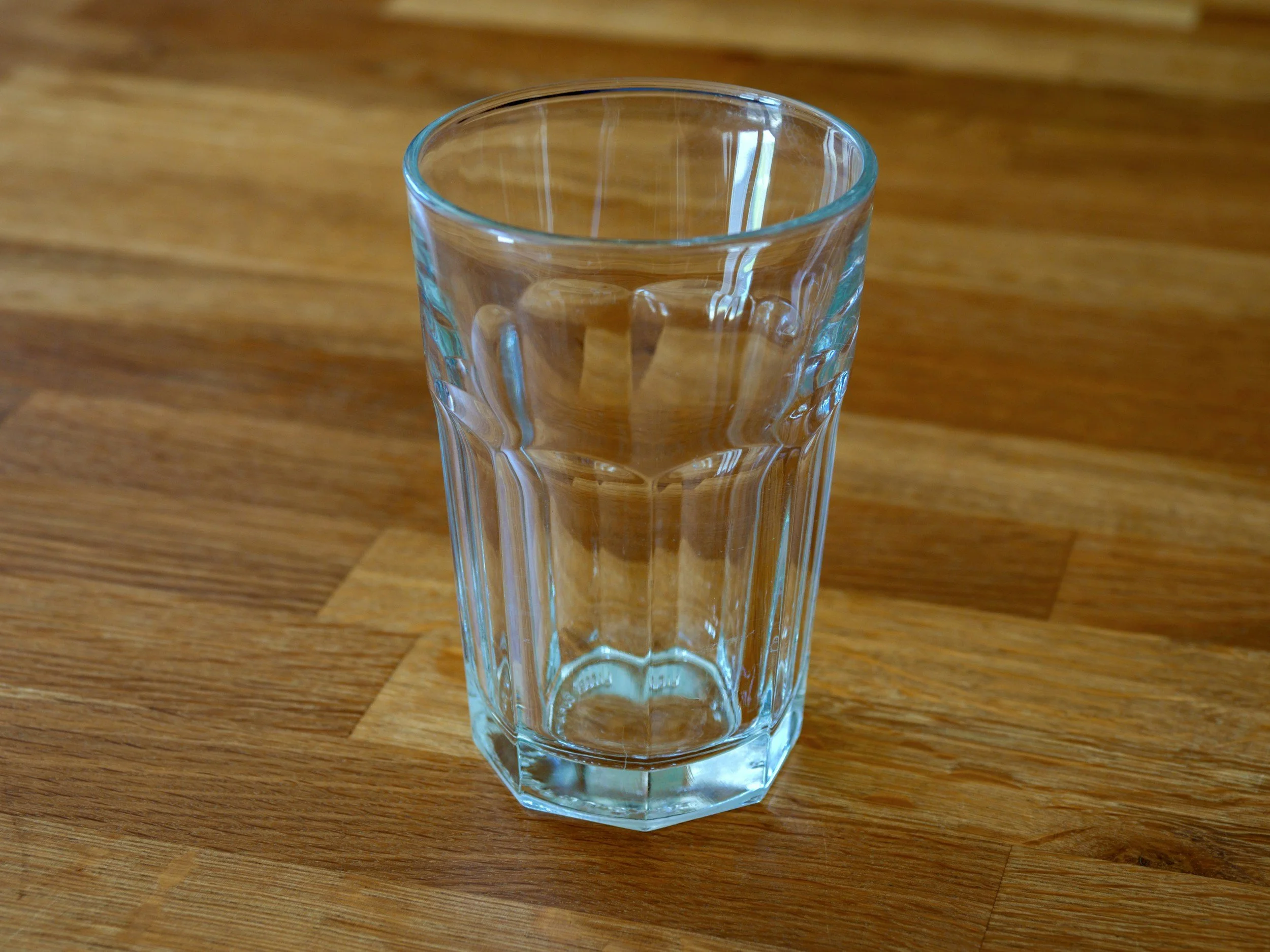 A clear glass of water on a wooden surface.