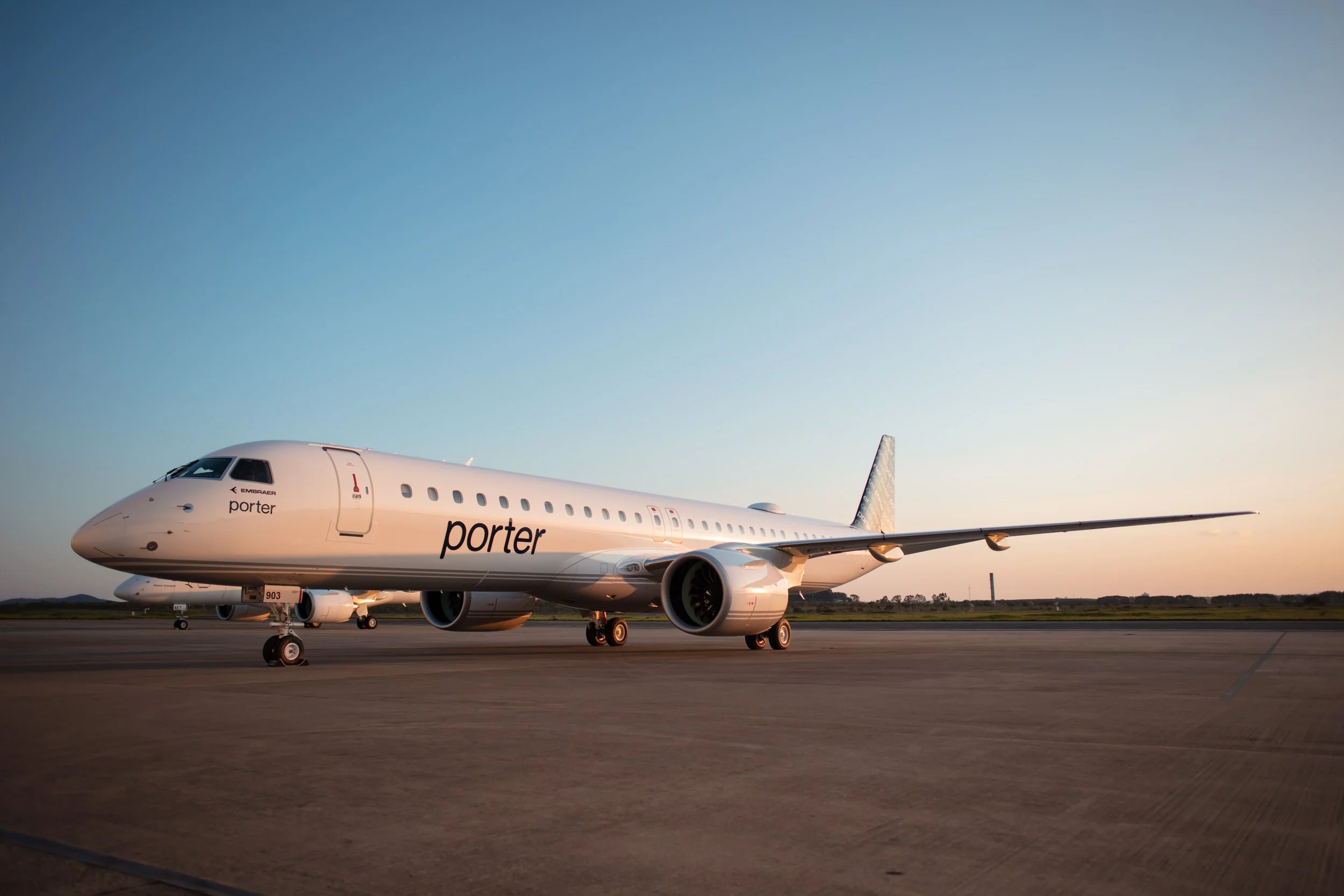 Commercial airplane on the tarmac at sunset, labeled 'porter', with a mostly clear sky in the background.