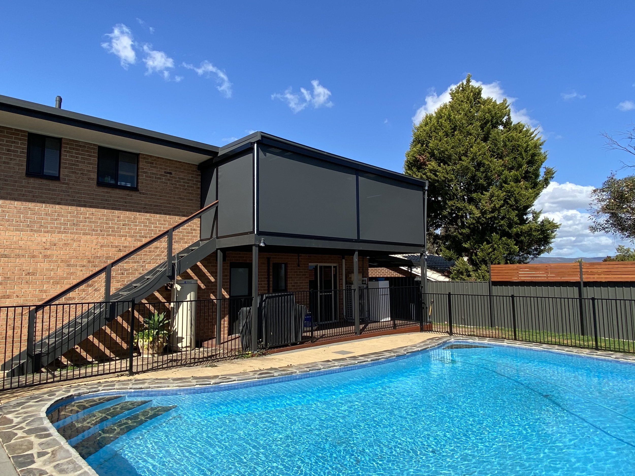 Outdoor blinds on the upper deck of a two-storey home with a pool