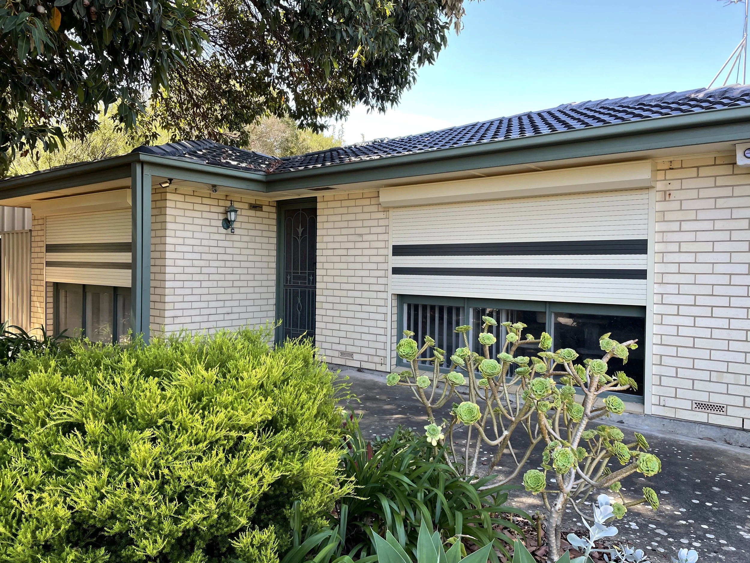 Cream roller shutters on a brick home, installed by Exteria Solutions