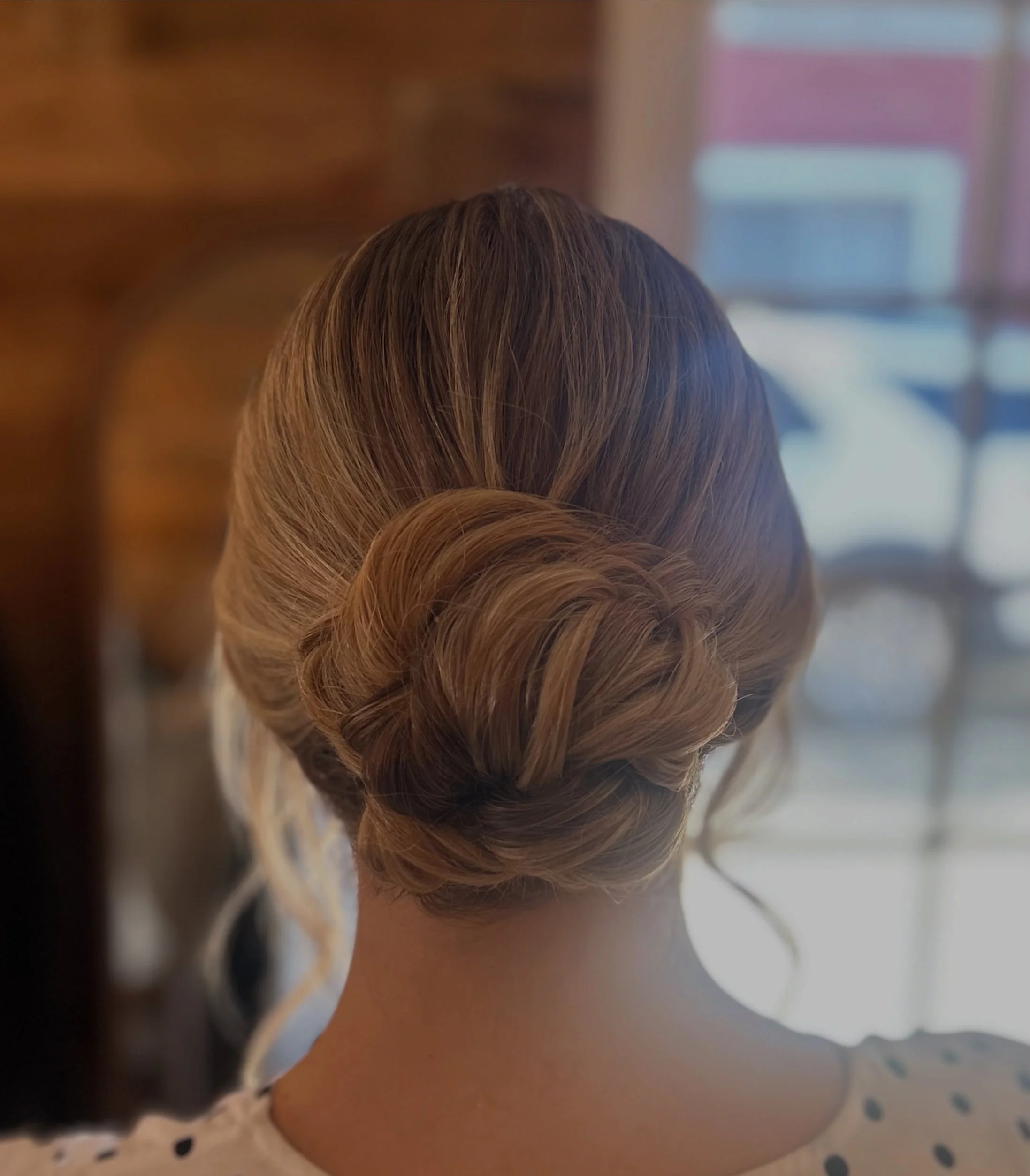 Close-up of a woman's head with brown hair styled in an elegant updo.