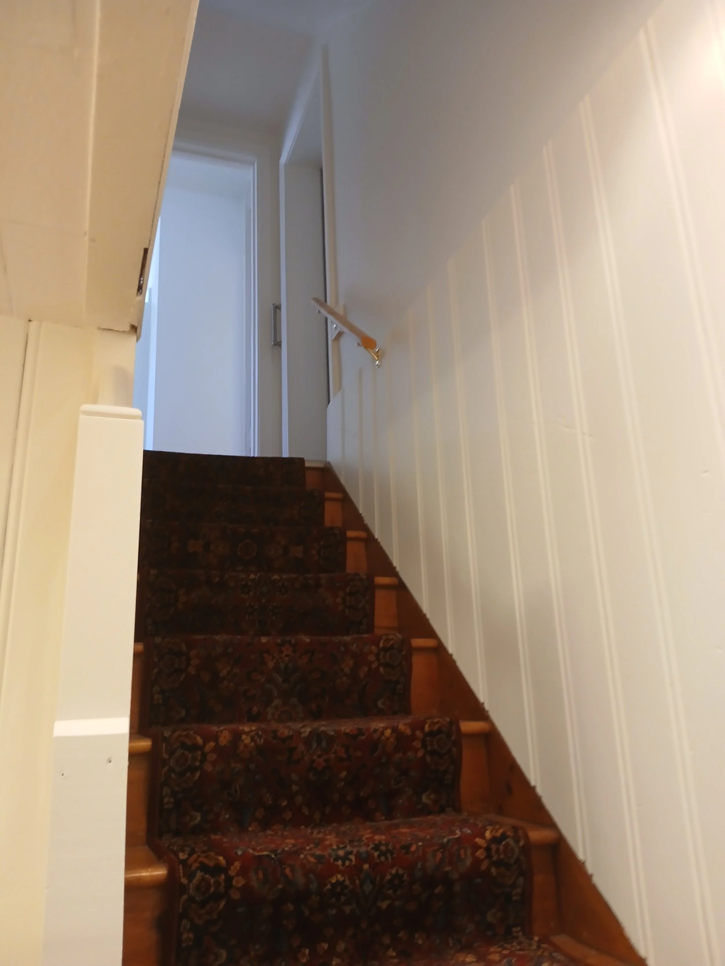 Westmount basement staircase with painted wall panelling beside dark wood steps