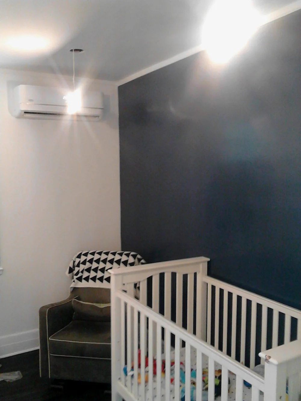 Nursery with a dark blue wall and white crib