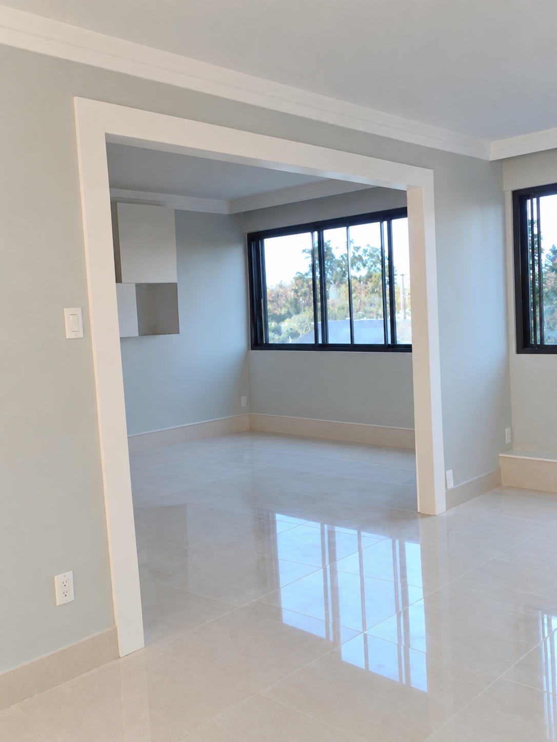 Freshly painted condo room with a wide opening, large windows and bright tile floor
