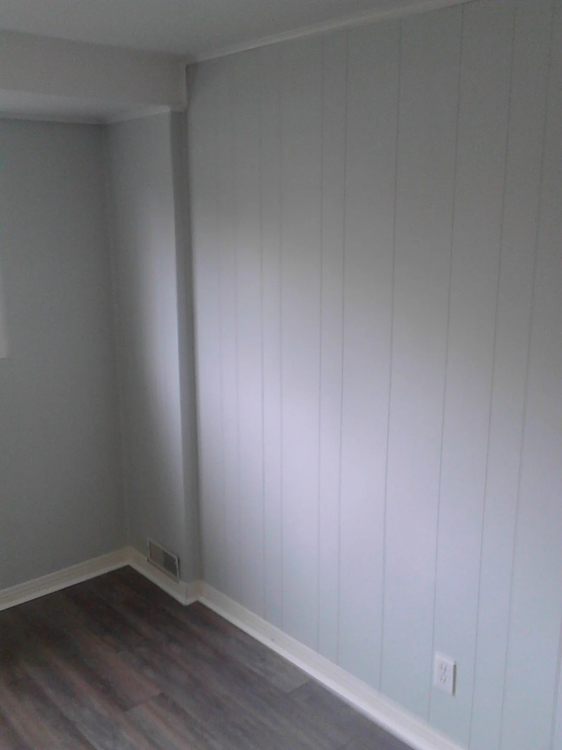 Beaconsfield room with light painted wood panelling, an empty floor and a window