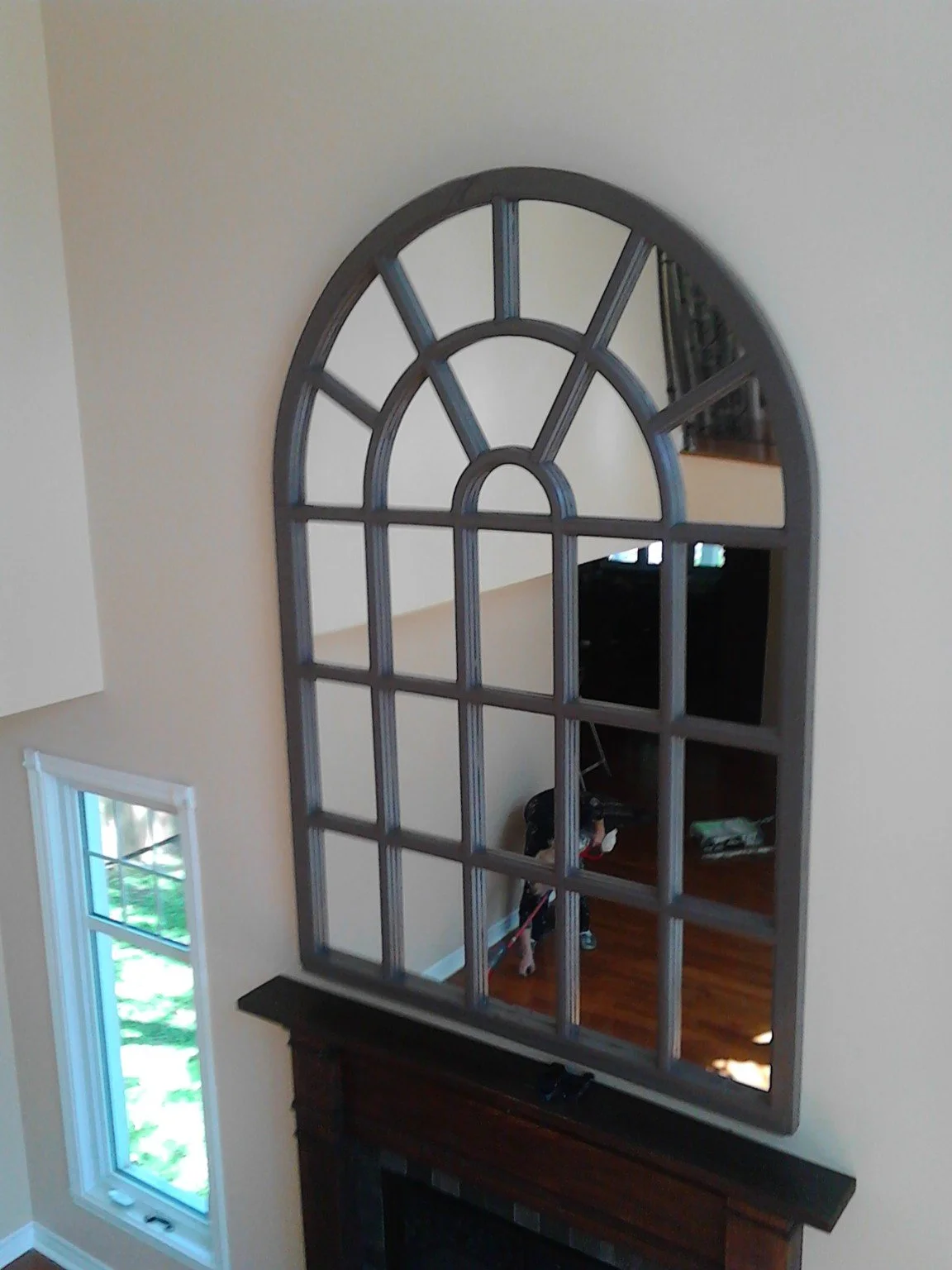 Arched painted mirror frame mounted high above a window