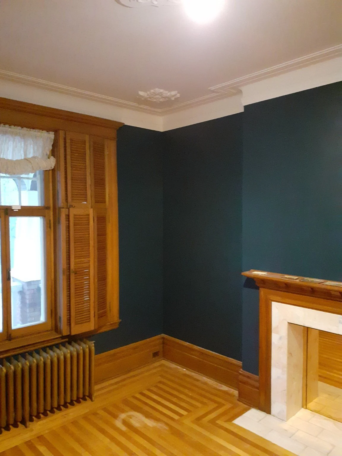 Angled view of the finished blue room with painted walls, crown moulding and fireplace