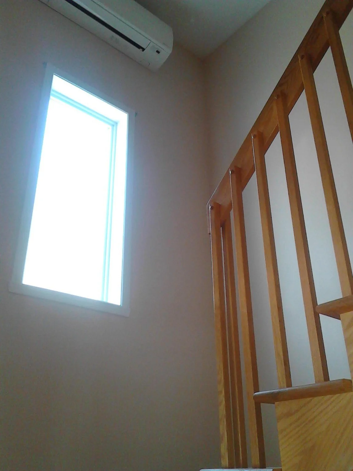 Painted stairwell wall beside a window and wood railing
