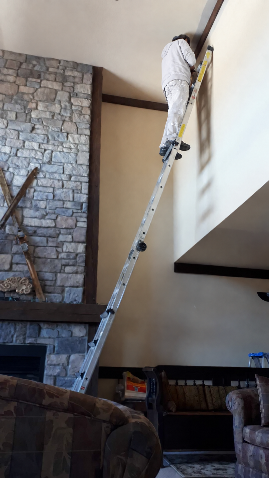 Joel working from a ladder in a vaulted living room