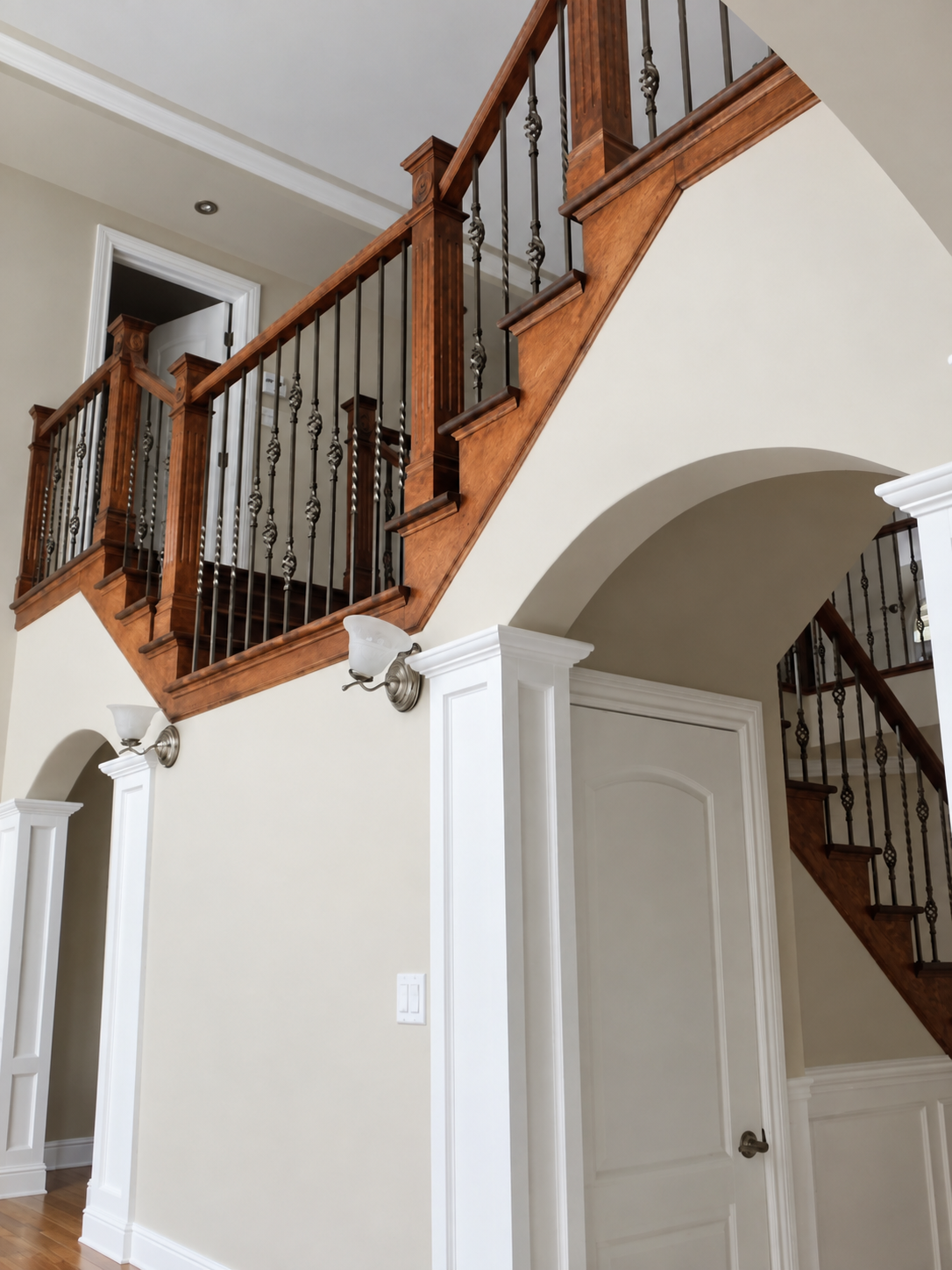 Wood staircase above an arched entryway with painted walls in Bois-Franc