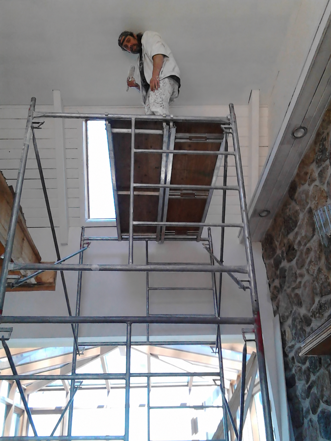 Joel working from a scaffold to reach a high interior wall