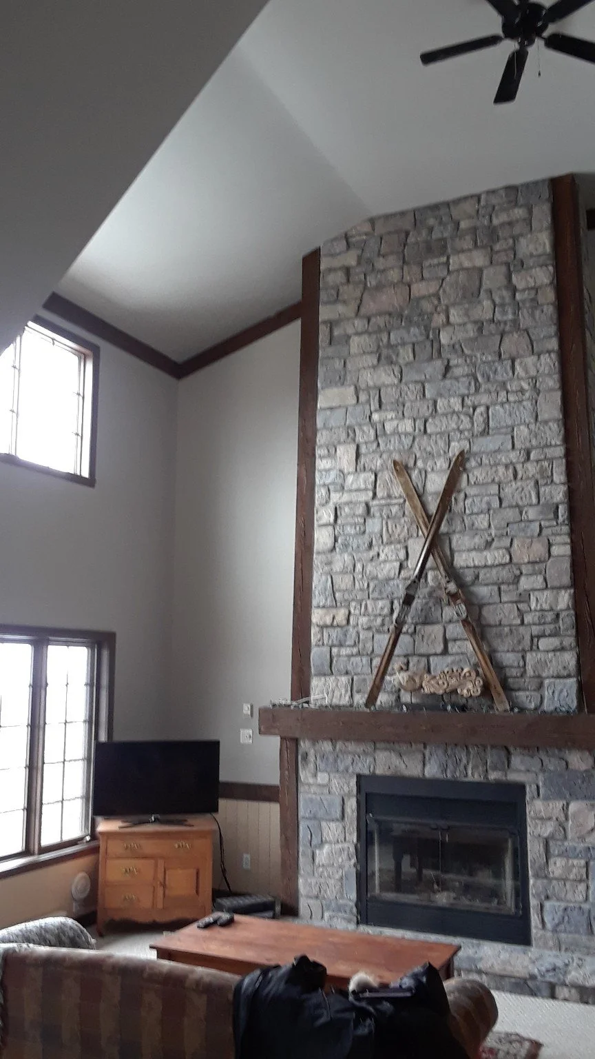 Tall painted walls around a stone fireplace and vaulted ceiling in Saint-Sauveur