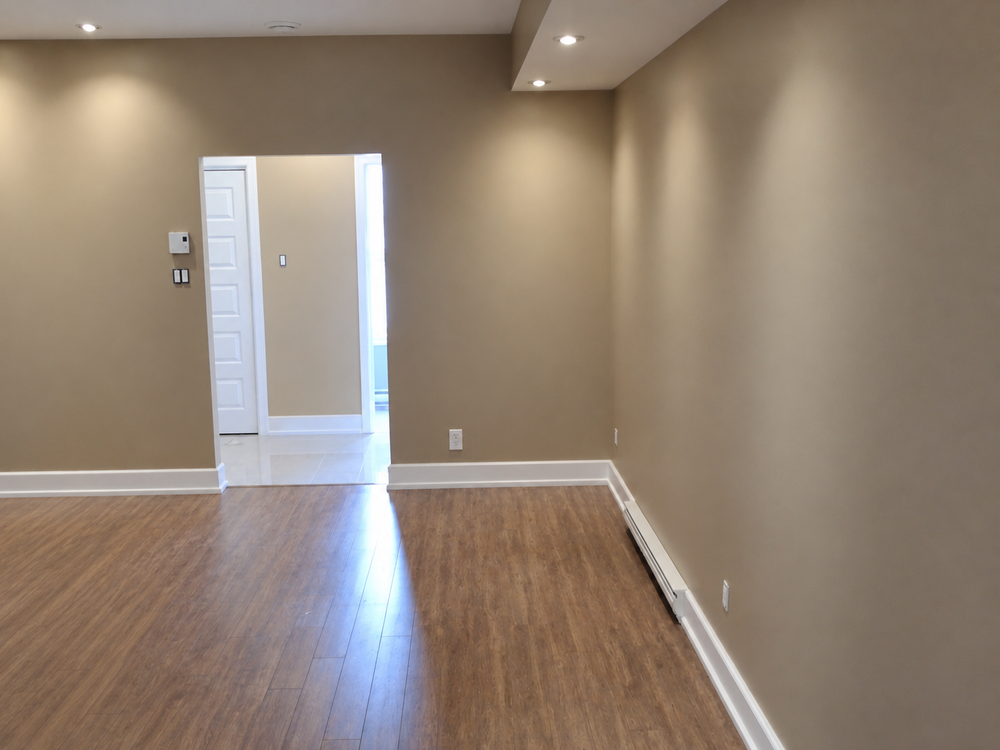 Empty condo living room with warm taupe walls and wood flooring