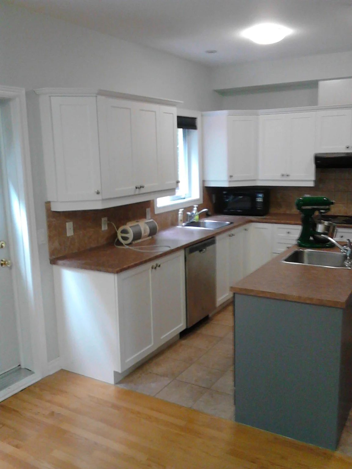 Another view of the Côte-Saint-Luc kitchen with white cabinetry and a grey island