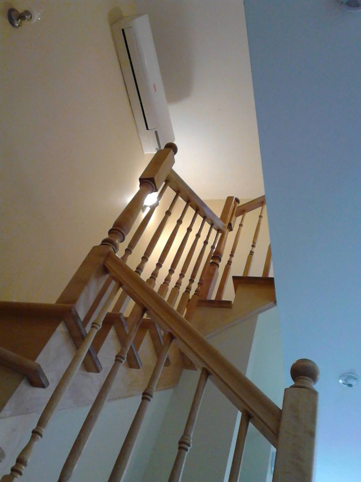 Wood staircase and railing beside a tall painted interior wall