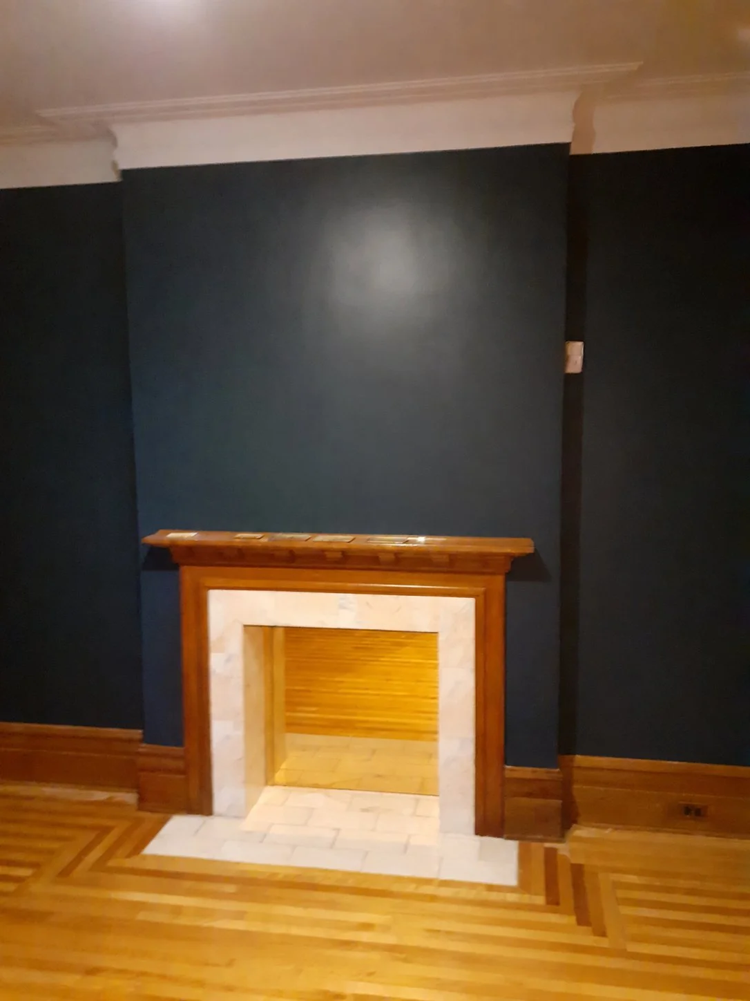 Front view of the blue accent walls, white crown moulding and wood fireplace