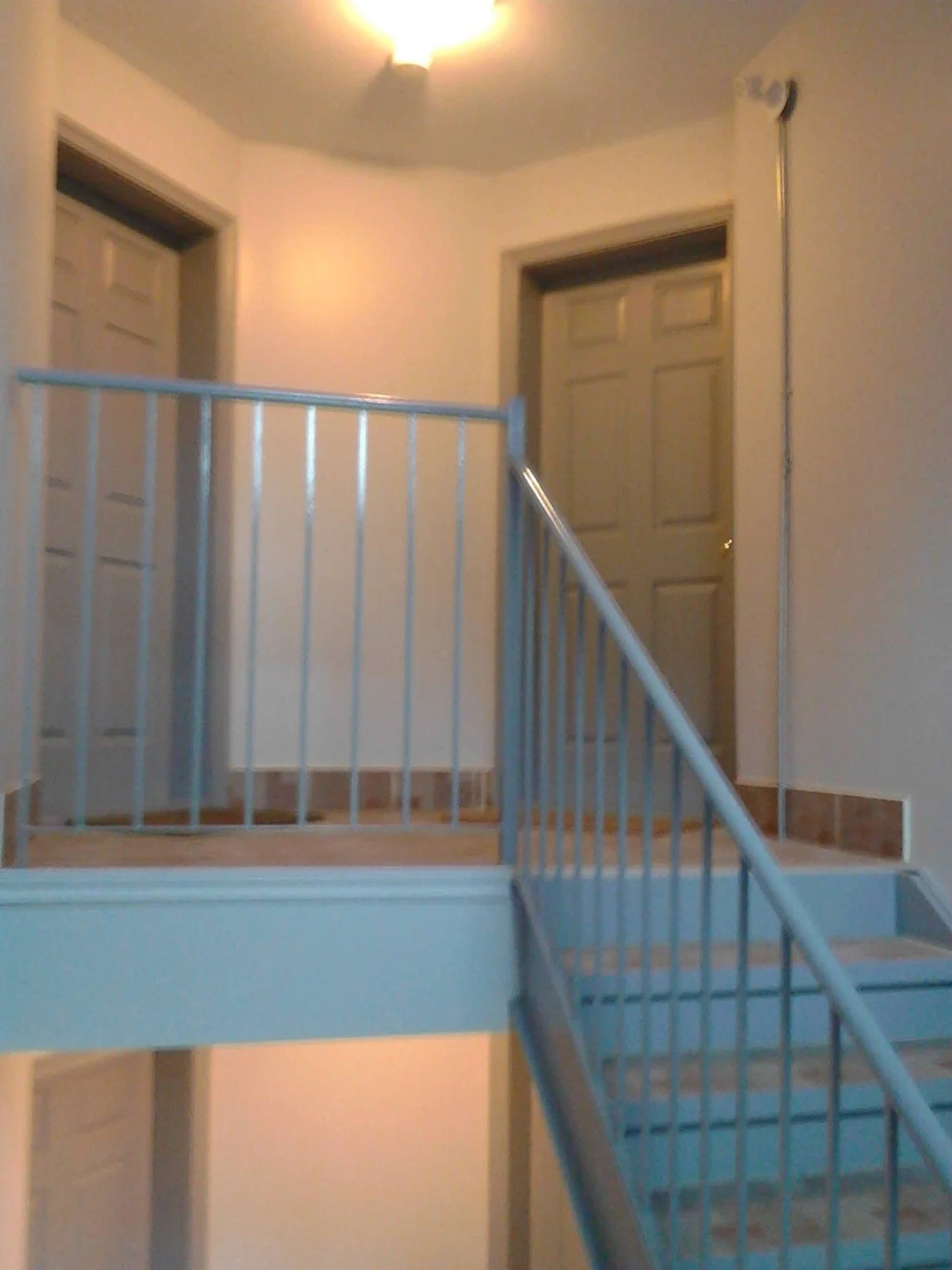 Condo common-area painting in a stairwell with pale blue steps, white walls and metal railings