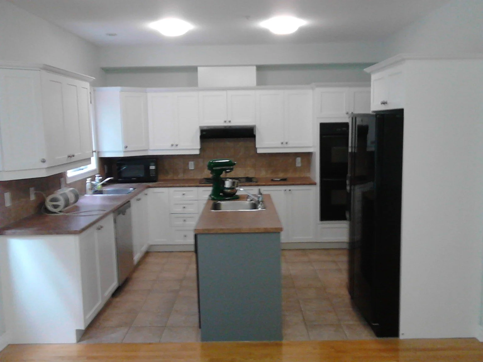 Côte-Saint-Luc kitchen with white cabinets, painted walls and a grey island