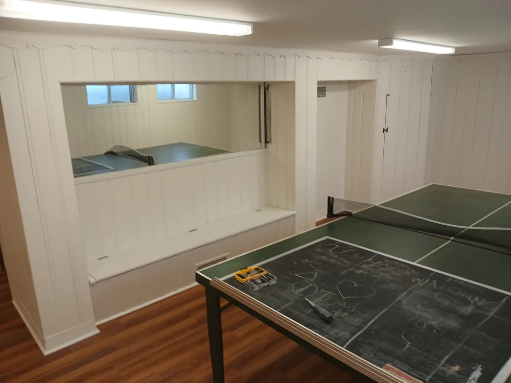 Basement games room with light painted wood panelling