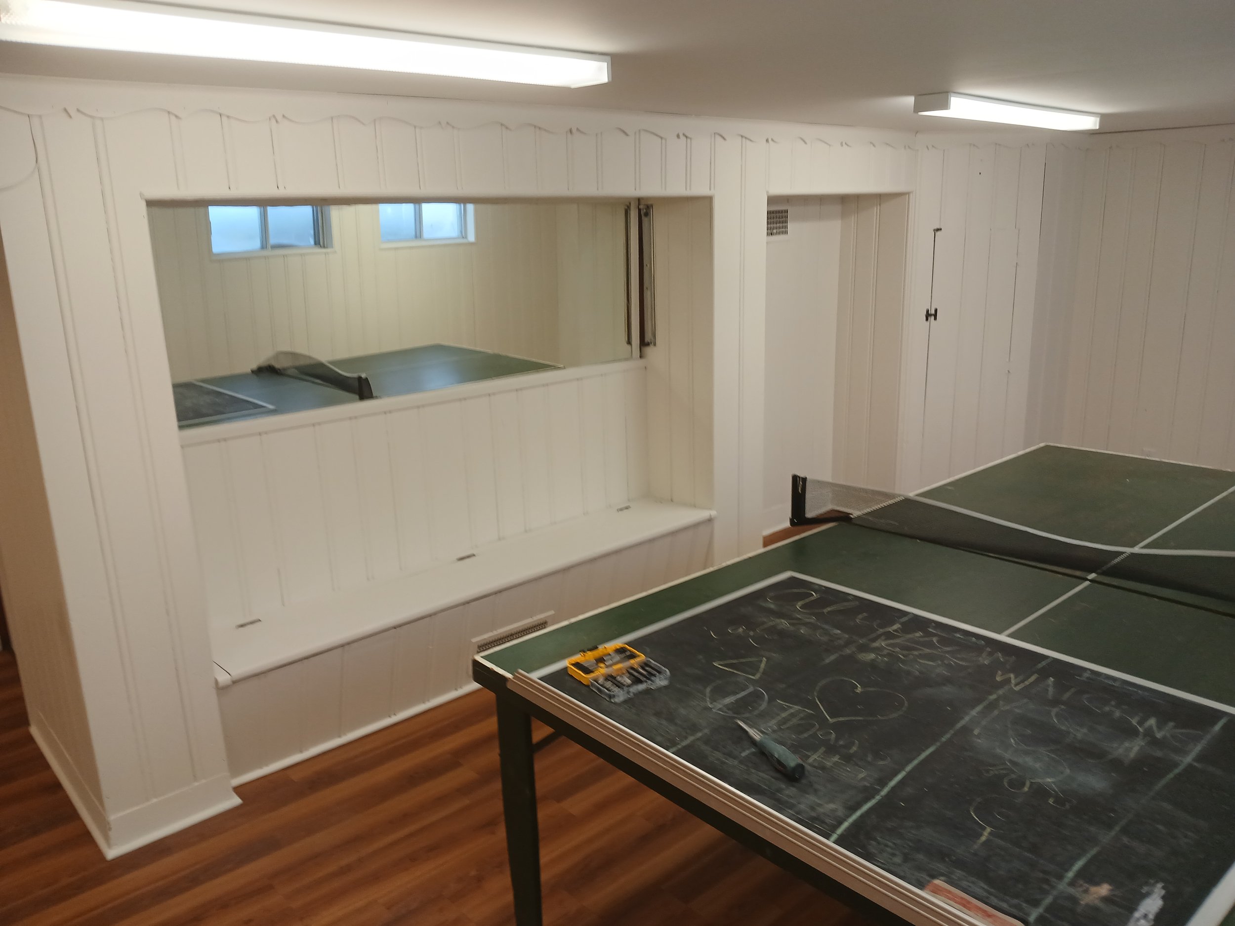 Westmount basement with light painted wood panelling and a games table