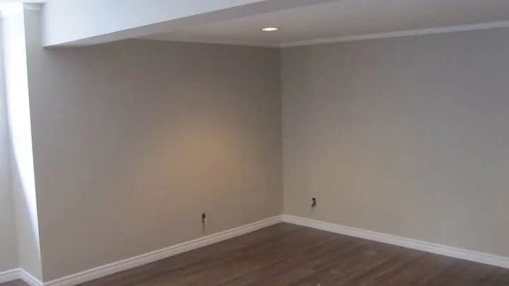Côte-Saint-Luc basement room with neutral painted walls and wood flooring