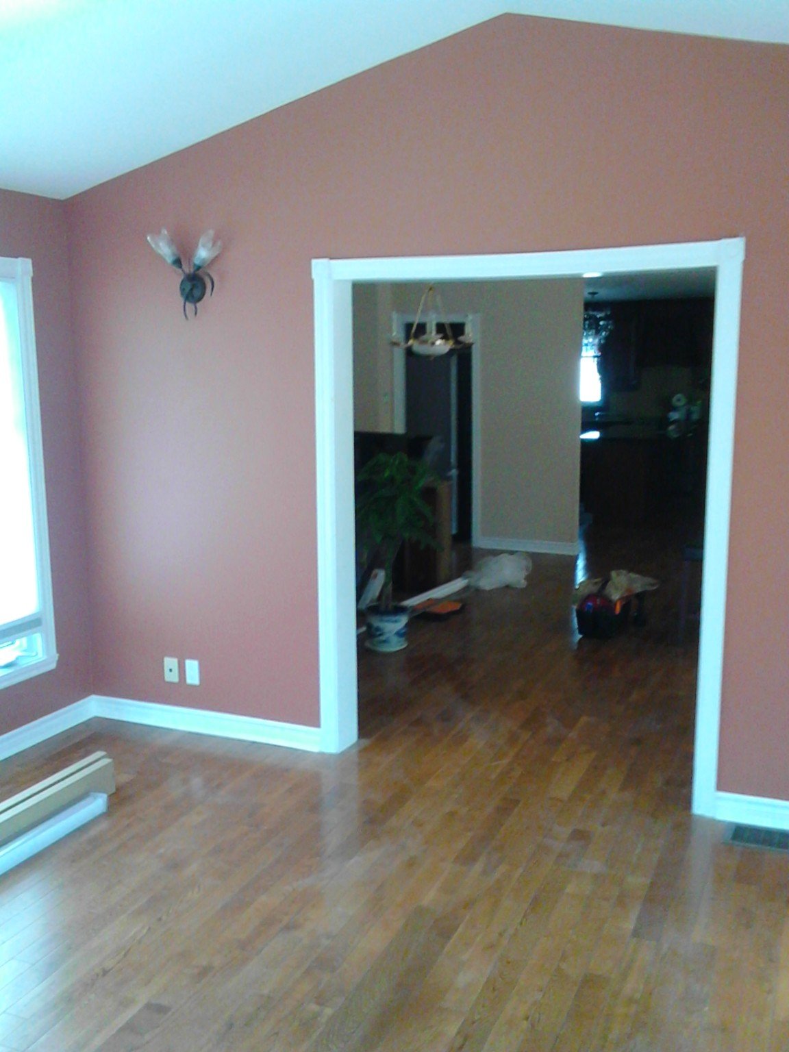 Interior room with muted red painted walls, white trim and wood flooring