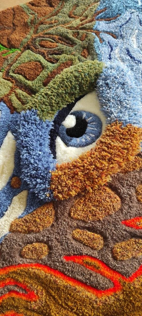 Gros plan des reliefs et des textures tuftées d'une œuvre de la collection "Ouvrez l'œil", mettant en valeur un œil réalisé en tufting manuel.