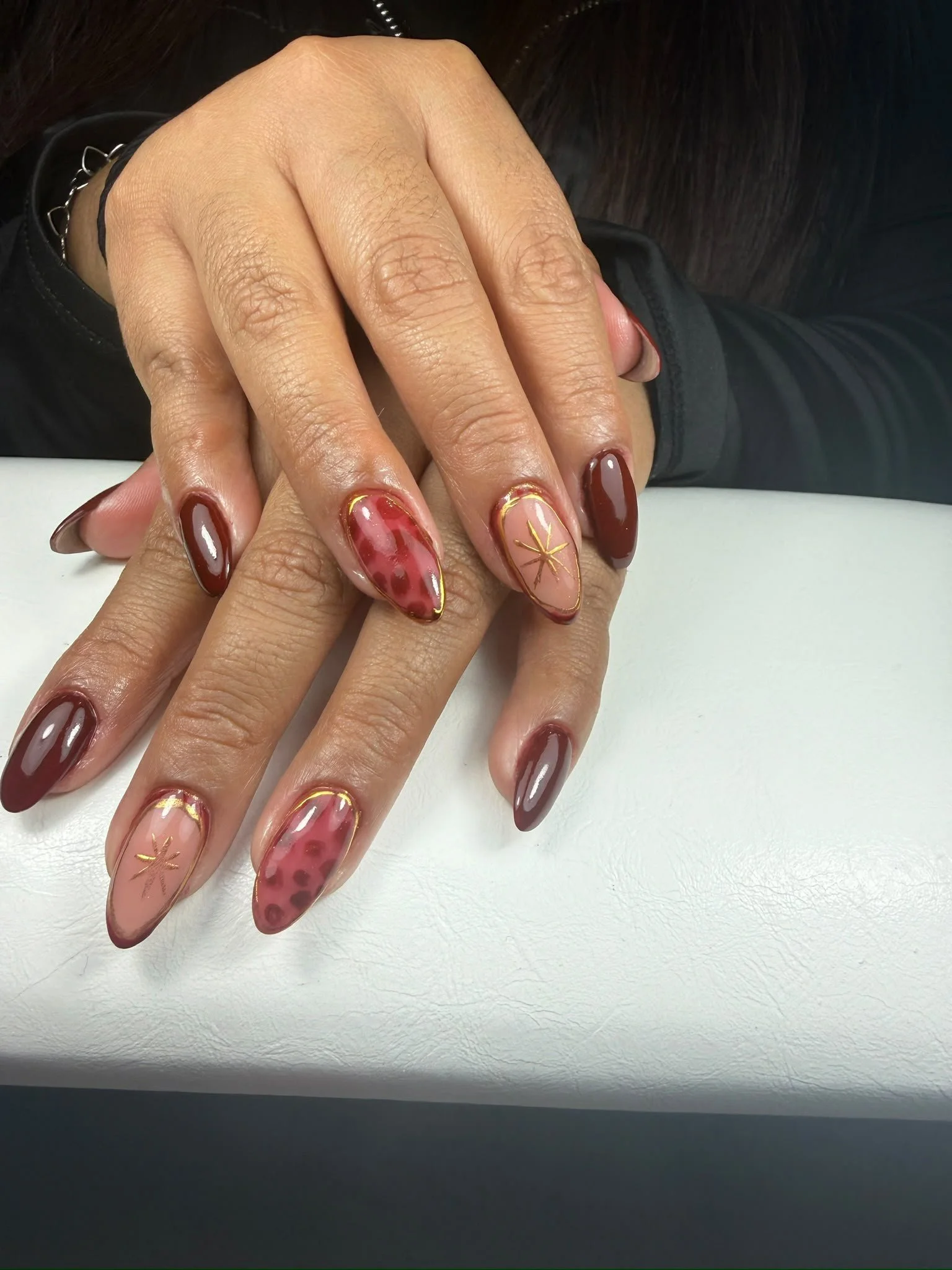 Nahaufnahme von Fingernägeln mit rotem, marbled und goldverzierten Nagellack