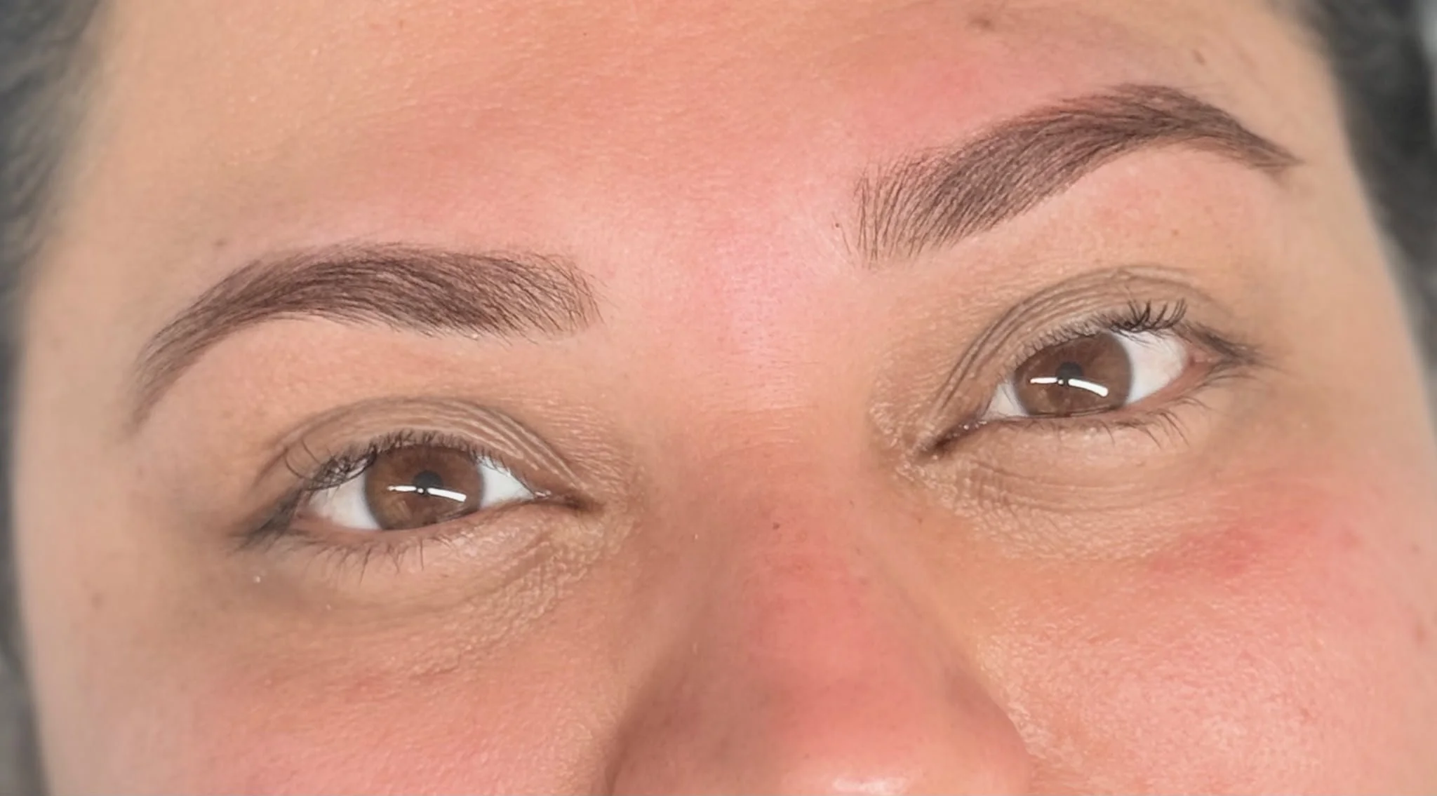 Nahaufnahme von braunen Augen und gepflegten, dunklen Augenbrauen.