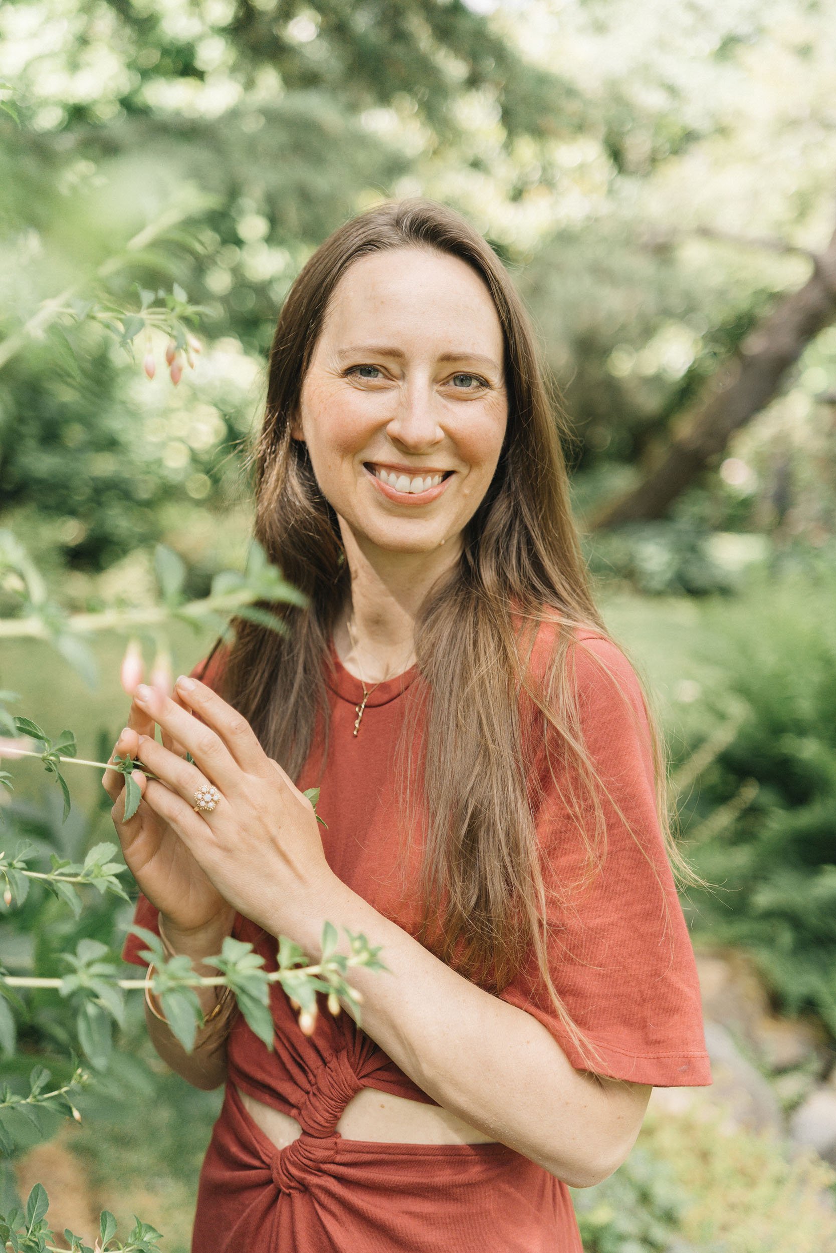 Hannah Glazko, founder of Inn Peace, smiling outdoors in a warm reddish top