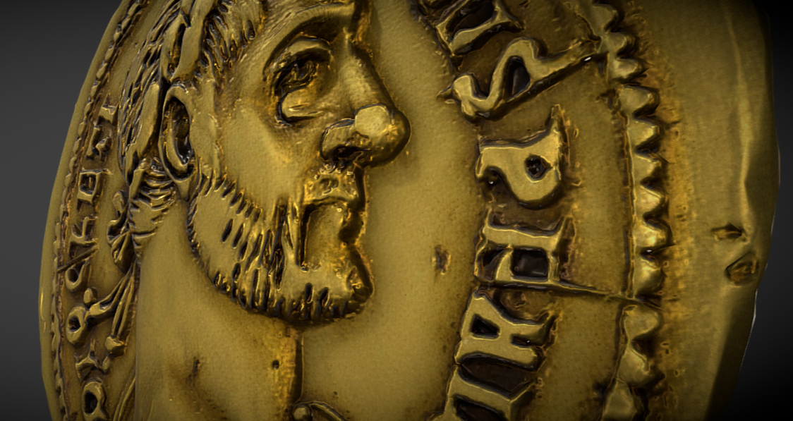 Close-up of a gold coin featuring the profile of a bearded man with long hair, likely a historical figure, with partially visible text on the coin.
