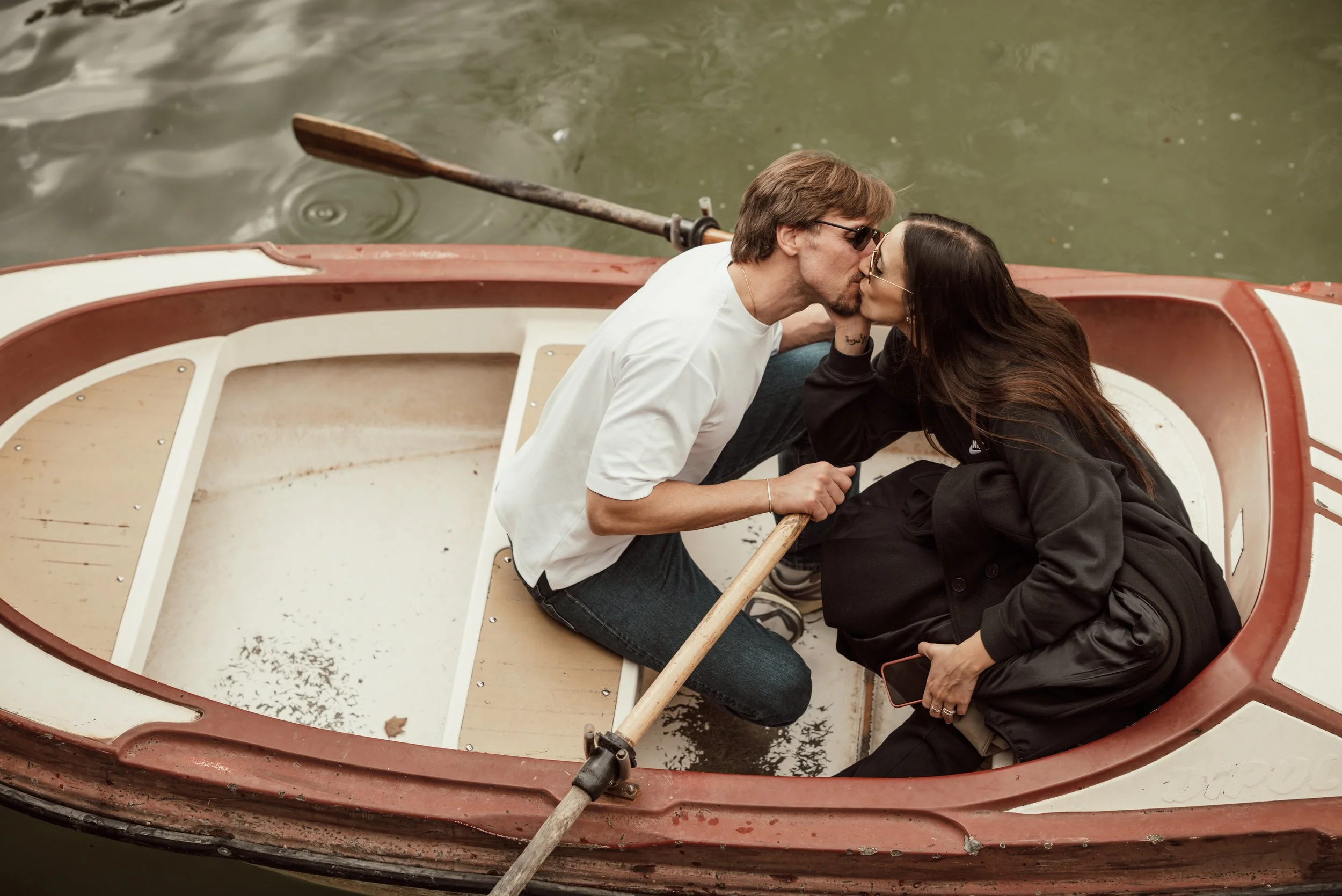 A couple sharing a kiss on a boat surrounded by water.