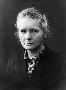 Black and white portrait of a woman with curly hair, wearing a dark top and a patterned collar.