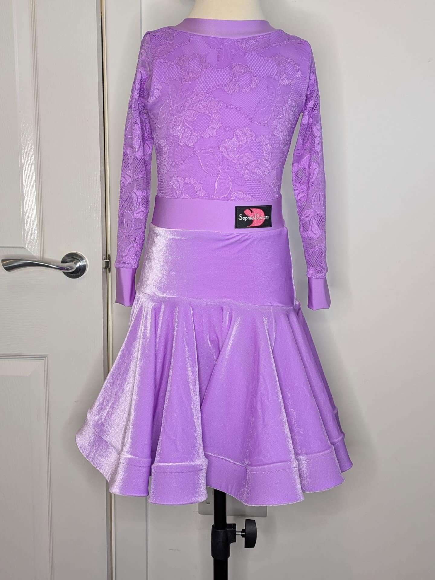 A purple dress with lace top and satin skirt displayed on a mannequin against a white door and wall.