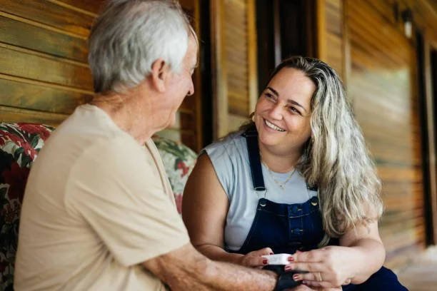 An adult daughter talking to her dad and smiling on their porch