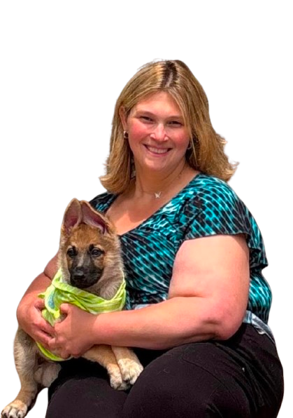 A smiling woman with blonde hair holding a German Shepherd puppy wearing a bright green bandana.