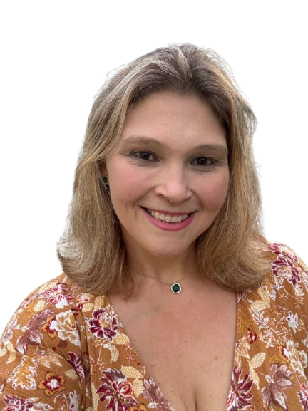 A woman with shoulder-length blonde hair, smiling, wearing a floral patterned top and a teal pendant necklace.