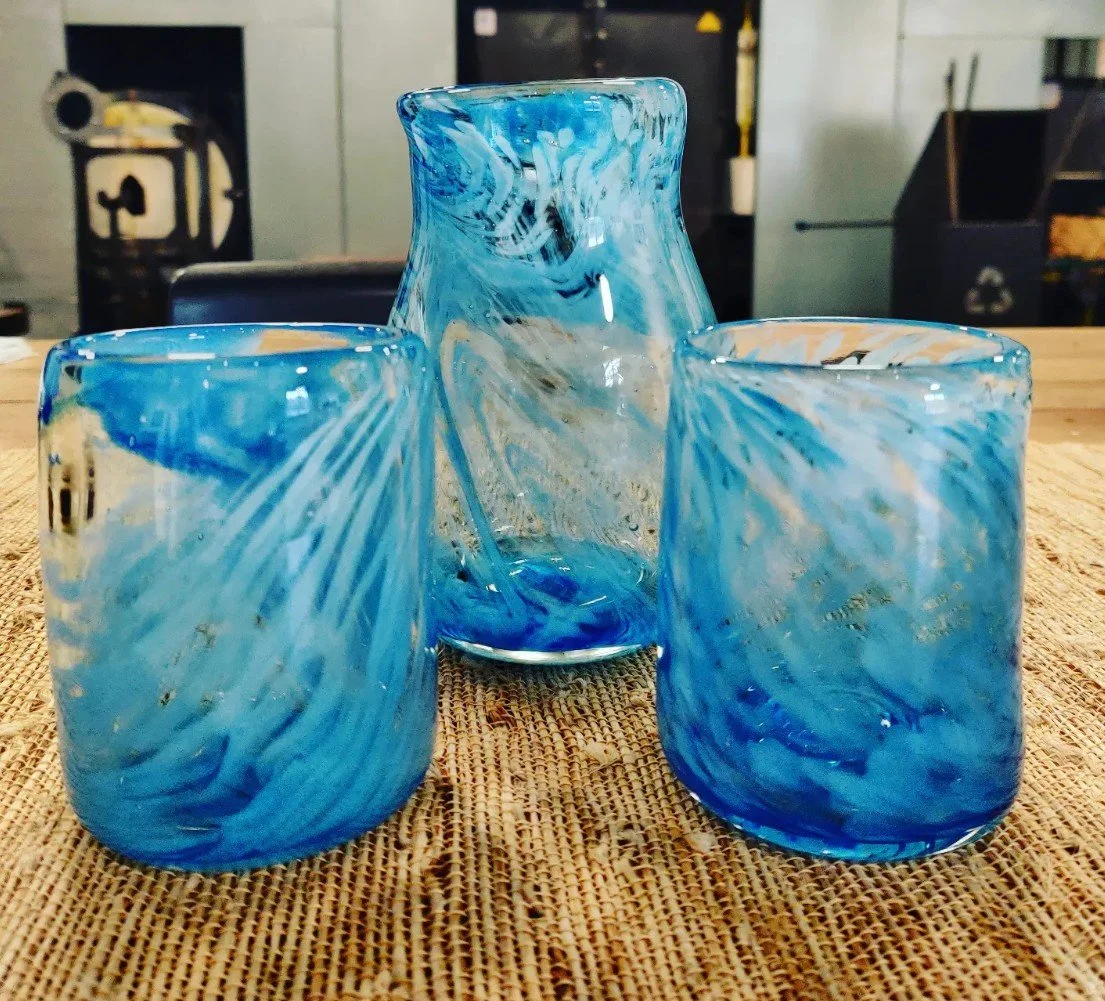 A blue and white marbled glass pitcher and two matching glasses on a wicker surface.