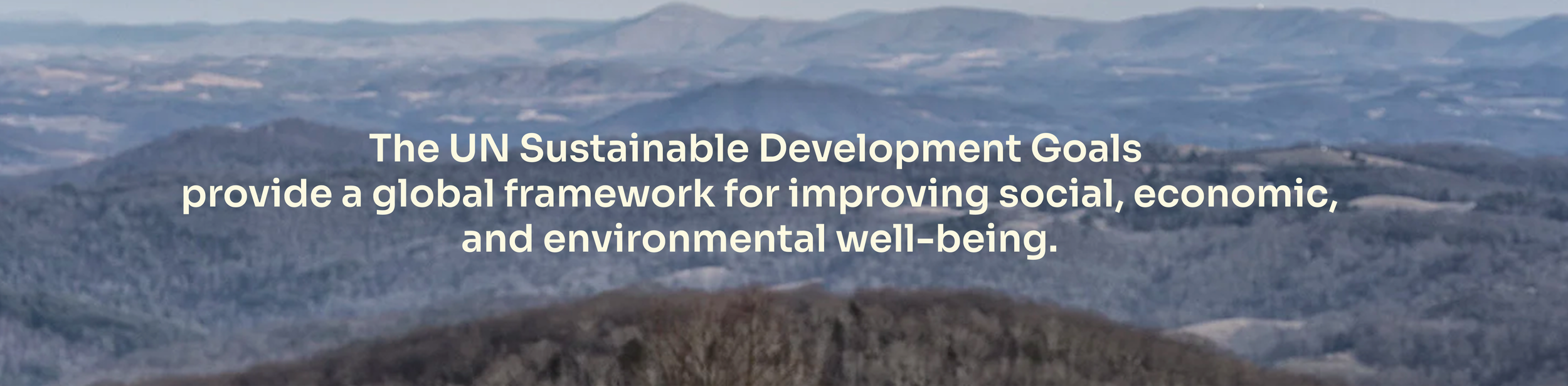 Text overlay on a mountainous landscape reading: "The UN Sustainable Development Goals provide a global framework for improving social, economic, and environmental well-being."
