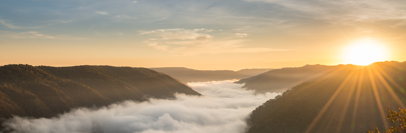 Morning sunrise over rolling green hills with fog in the valley.