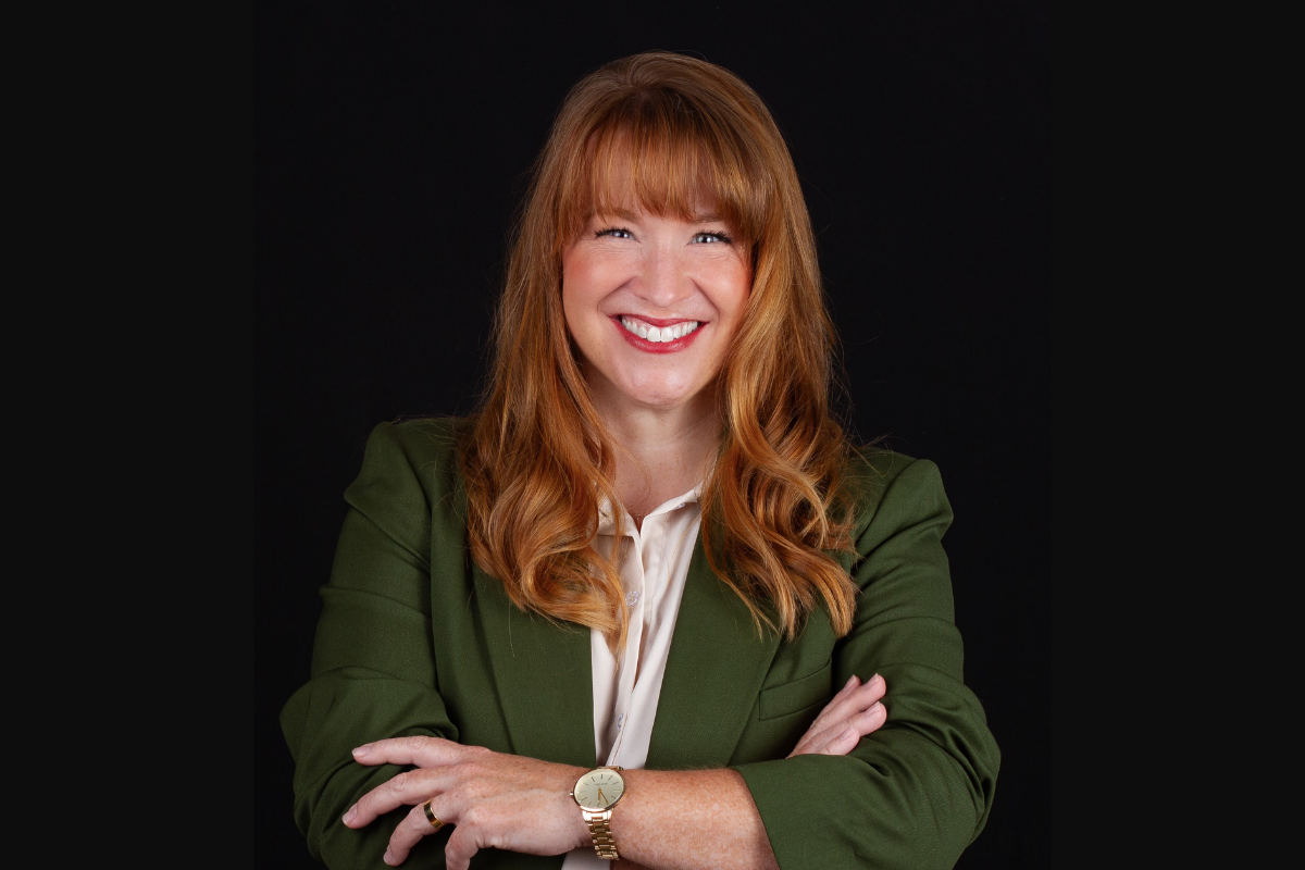 Headshot of Lindsay James standing in front of dark background