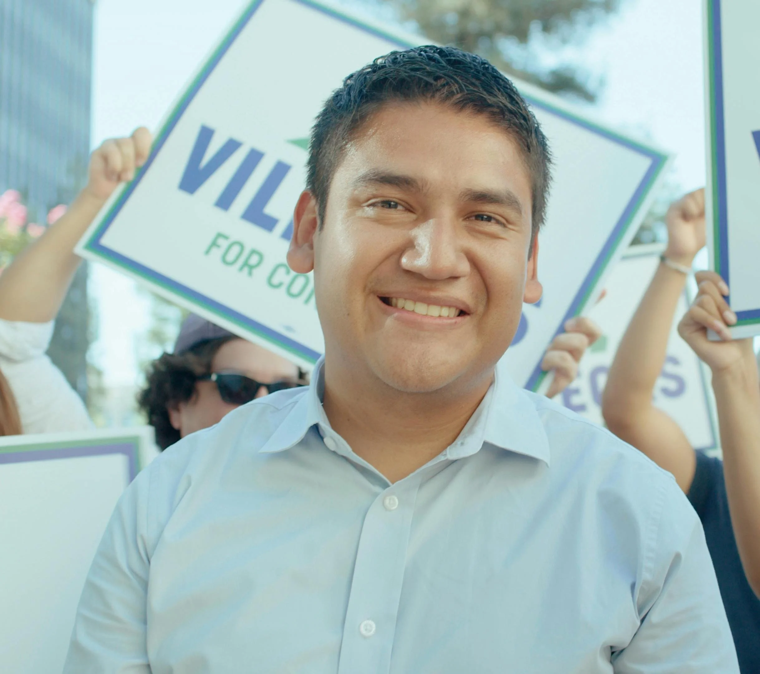 Headshot of Randy Villegas in front of a crowd holding campaign posters