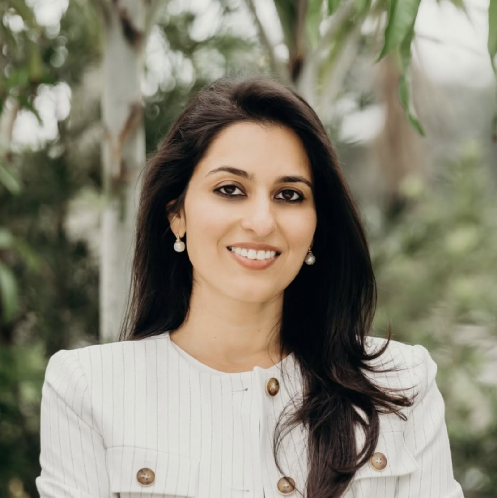 Headshot of Pia Dandiya, she is standing outside in front of greenery