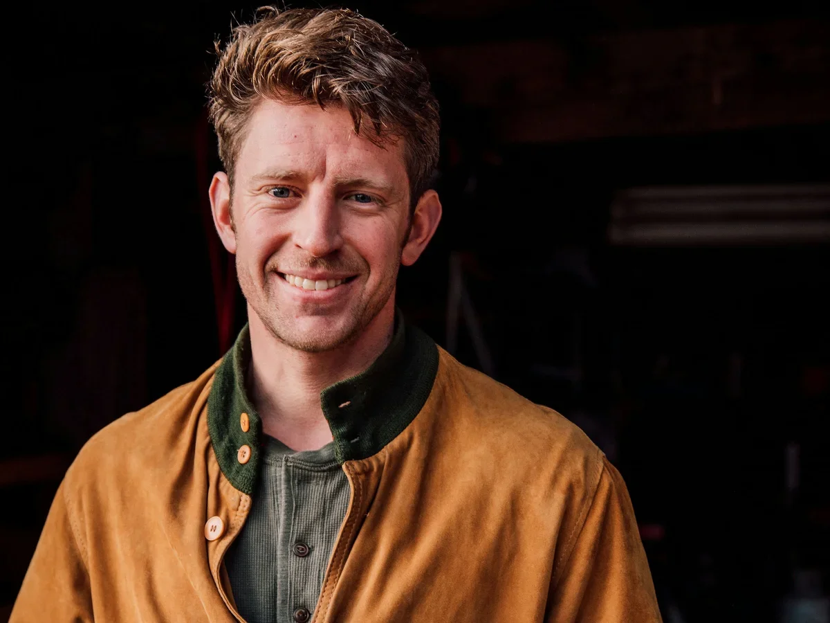 Headshot of Sam Forstag standing in front of a dark background