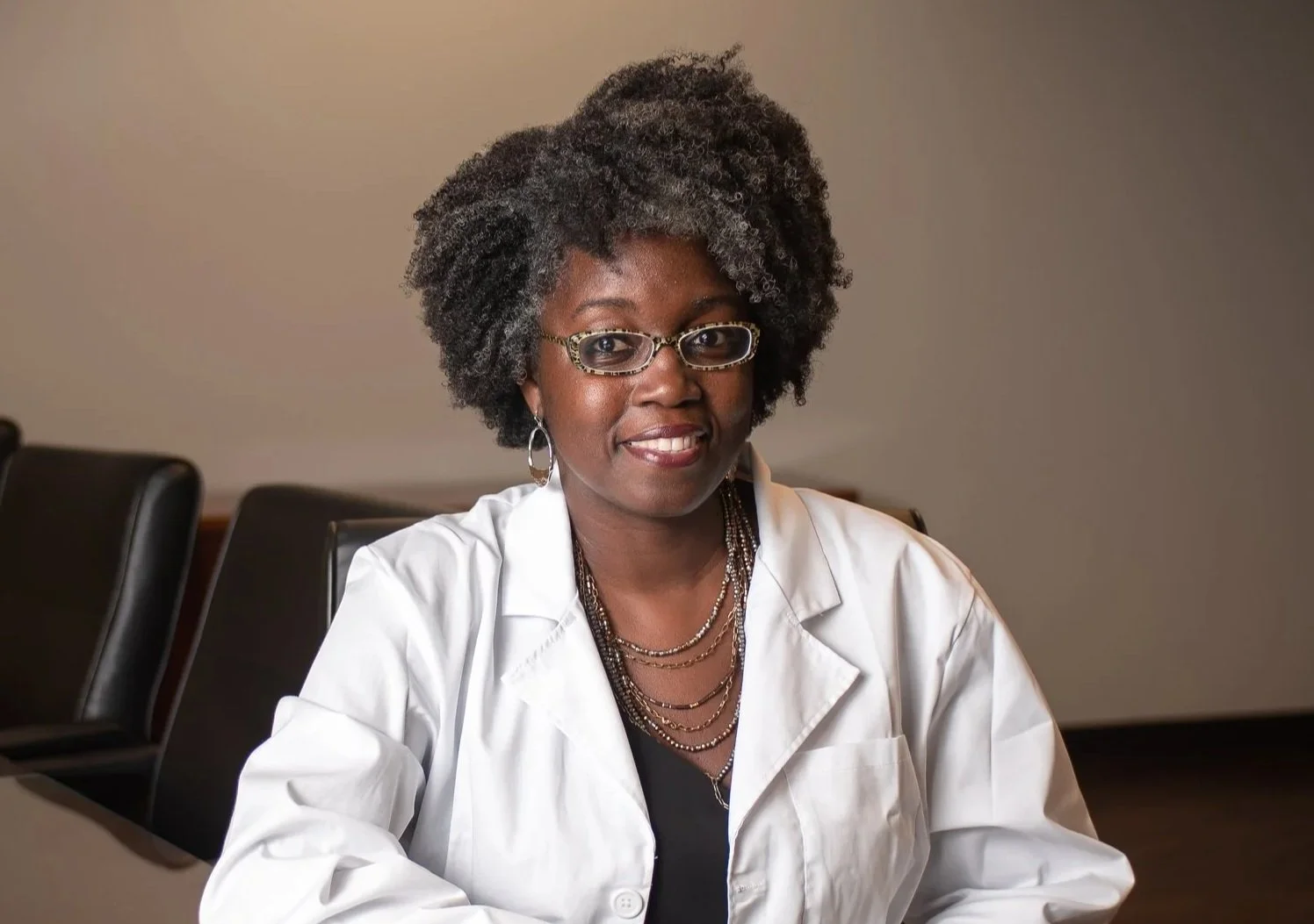 Headshot of Jasmine Clark sitting at a table in her lab coat