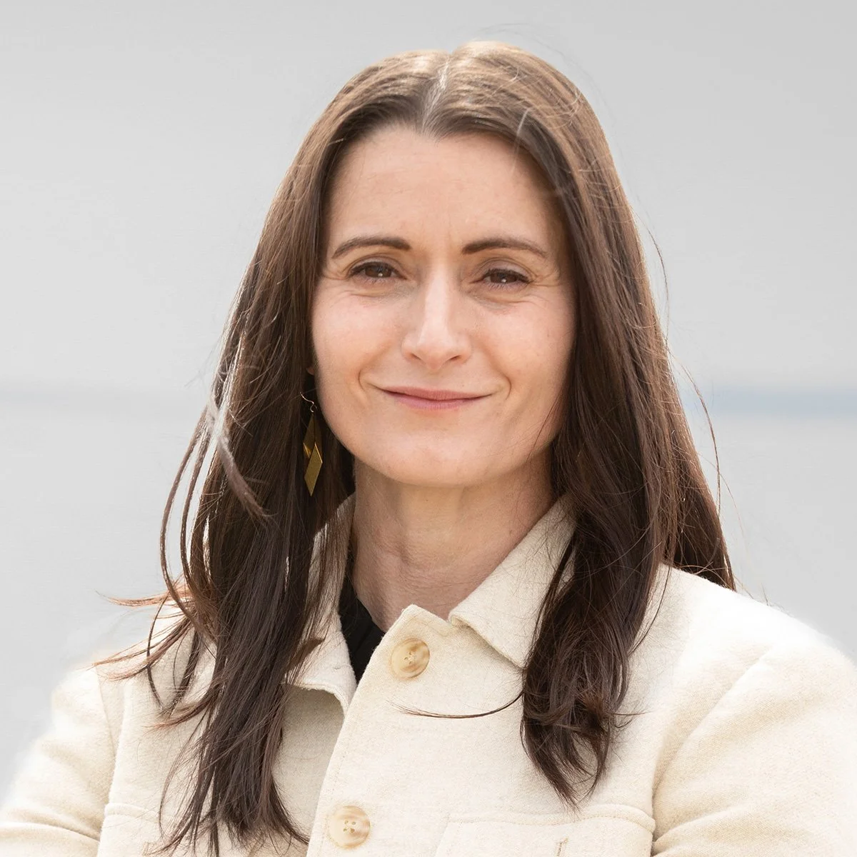 Headshot of Cait Conley smiling with a river behind her