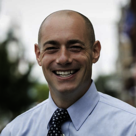 Smiling bald man in business attire standing outdoors