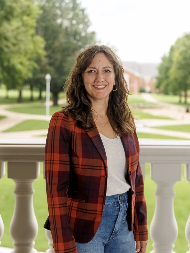 A headshot of Stephanie wearing a red plaid jacket